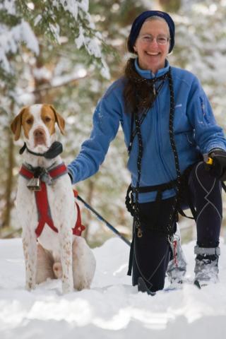 Dr. Johanna Kaufman kneeling in the snow with her dog Isaac